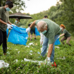 Volunteers picking up garbage while cleaning public park, they are wearing protective face masks for protection against virus during covid-19 pandemic