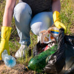 Volunteer girl in yellow gloves collects garbage selective focus