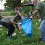 Multi-ethnic group of volunteers cleaning public park during coronavirus pandemic, they are wearing protective face masks